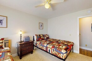 Ein Schlafzimmer mit einem Bett, einem Nachttisch, einer Lampe und einem Deckenventilator.