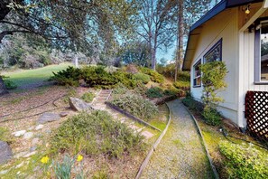 Ein Weg führt zu einem Haus mit Garten und einer Holzterrasse.