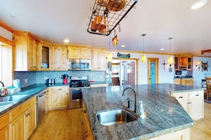 A kitchen with wooden cabinets, granite countertops, stainless steel appliances, and pendant lighting. - Humphreys Lakefront - Private Dock, Sleeps 24 (Bass Lake)