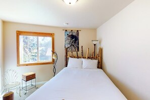 Un dormitorio con una cama, una ventana, una silla y una mesita.