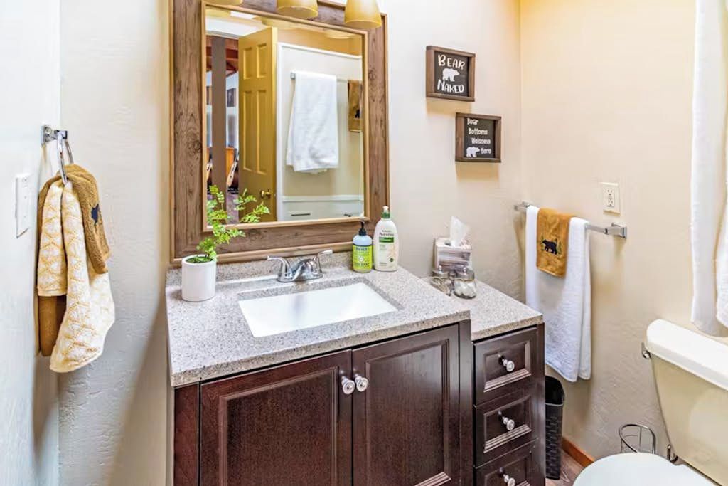 A bathroom with a sink, mirror, cabinets, and a towel rack.