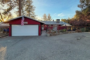 Eine rote Garage mit weißer Garagentür, einer amerikanischen Flagge und einem kleinen Vorbereich mit Holzzaun.
