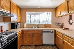 A kitchen with wooden cabinets, a stove, a dishwasher, and a window with blinds. - Miglin Lakeview - Lake Views & Private Boat Slip (Bass Lake)