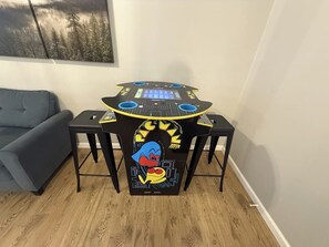 Mesa de DJ com design de personagem de desenho animado, sofá cinza e um quadro na parede.
