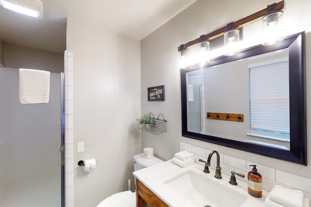 A bathroom with a large mirror, a sink with a faucet, a toilet, and a towel rack.