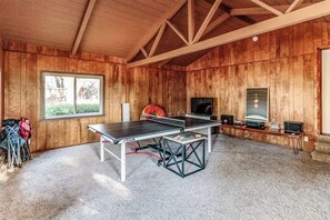 A room with a ping pong table, a television, and a window with a view of trees. - Pine Ridge Peak - Game Room, Near Lake & Yosemite (Oakhurst)