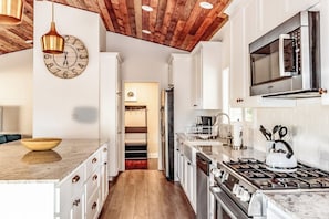 A kitchen with a wooden ceiling, white cabinets, a stainless steel stove, and a microwave. - Pine Ridge Peak - Game Room, Near Lake & Yosemite (Oakhurst)