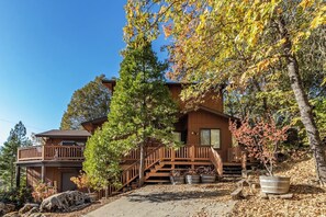 A two-story cabin with a wooden deck and a staircase leading to the entrance. - Alder Lake View Lodge (Bass Lake)
