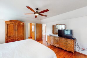 A bedroom with a bed, wooden wardrobe, dresser, television, and a ceiling fan. - Alder Lake View Lodge (Bass Lake)