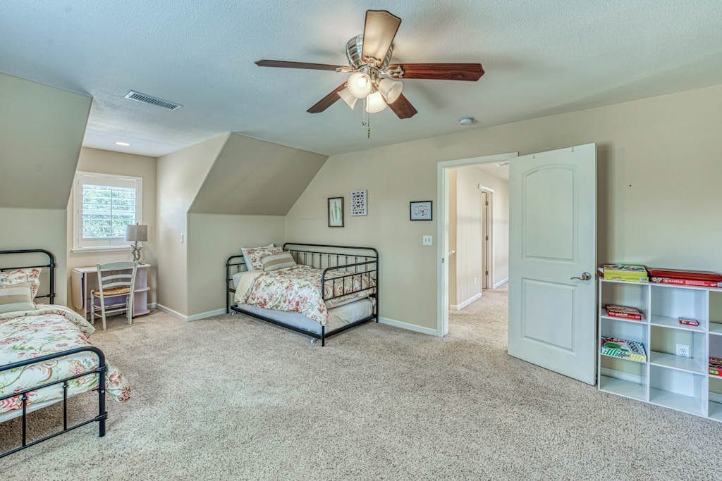 A bedroom with a bed, a ceiling fan, a window, and a door.