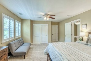 Ein Schlafzimmer mit einem Bett, einer Bank, einem Deckenventilator und einer Tür.