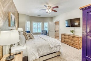 A bedroom with a bed, bedside table, lamp, ceiling fan, dresser, TV, and a door. - Wooded Bliss - Near Yosemite, Sweeping Views (Mariposa)
