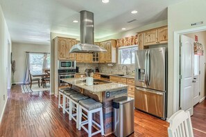 A modern kitchen with wooden cabinets, stainless steel appliances, and a central island with bar stools. - Wooded Bliss - Near Yosemite, Sweeping Views (Mariposa)