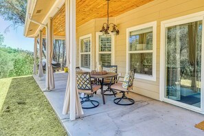 A covered patio with a table and chairs, large windows, and a wooden ceiling. - Wooded Bliss - Near Yosemite, Sweeping Views (Mariposa)