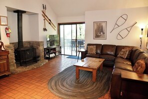 A living room with a stone fireplace, leather sofa, and a wooden coffee table. - Forest Glen - Secluded Cabin Inside Yosemite (Yosemite West)
