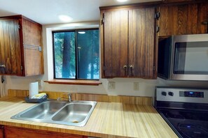 A kitchen with wooden cabinets, a double sink, a microwave, and an oven. - Forest Glen - Secluded Cabin Inside Yosemite (Yosemite West)