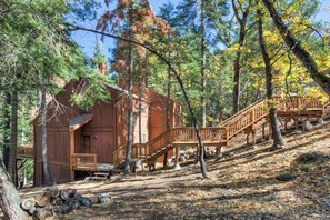 A rustic cabin with a wooden staircase leading to a deck, surrounded by trees. - Forest Glen - Secluded Cabin Inside Yosemite (Yosemite West)