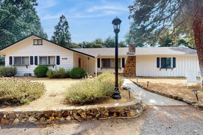 A single-story house with a stone foundation, a front porch, and a pathway leading to the entrance. - Uhre Family Retreat - Game Room & Spacious Deck (Oakhurst)