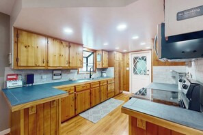 A kitchen with wooden cabinets, a black countertop, and a stove. - Uhre Family Retreat - Game Room & Spacious Deck (Oakhurst)