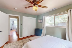 A bedroom with a bed, a ceiling fan, a window with curtains, and a door leading to another room. - Uhre Family Retreat - Game Room & Spacious Deck (Oakhurst)