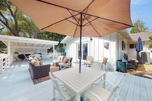 A covered outdoor patio with a table and chairs, a white fence, and a pergola. - Uhre Family Retreat - Game Room & Spacious Deck (Oakhurst)