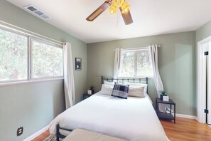 A bedroom with a bed, two bedside tables, a ceiling fan, and large windows. - Uhre Family Retreat - Game Room & Spacious Deck (Oakhurst)