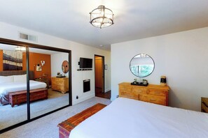 A bedroom with a large bed, a wooden dresser, a mirror, and a television on the wall. - Yosemite Big Rock Cabin (Fish Camp)