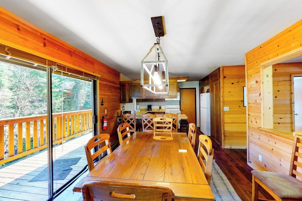 Un interno in legno con un grande tavolo da pranzo, sedie e una lampada a sospensione.