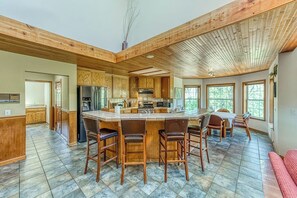 A spacious kitchen with a central island, wooden cabinets, and a large window providing natural light. - Cascadel Haven - Mountain Views & Dog-Friendly (North Fork)