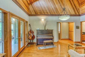 A spacious living room with a grand piano, a cello, and a bench. - Cascadel Haven - Mountain Views & Dog-Friendly (North Fork)