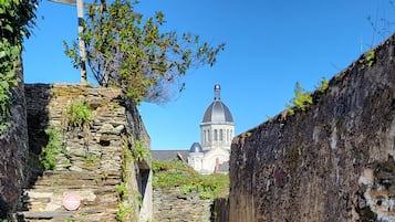 Un chemin de pierre mène à un bâtiment surmonté d’un dôme, lequel est entouré de murs de pierre et de végétation.