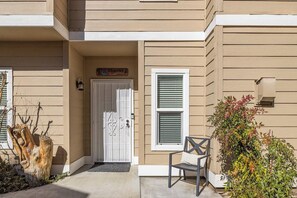 Un immeuble résidentiel avec une porte d’entrée, un banc et un petit espace jardin.