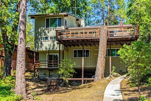 A two-story cabin with a deck, surrounded by trees. - Todds Lakefront House (Bass Lake)