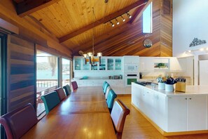 A spacious kitchen with white cabinets, a central island, and a dining area with wooden tables and chairs. - Peters Lakefront - Dock, Pool Table & Lake Views (Bass Lake)