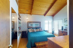 A bedroom with a wooden ceiling, a bed with a blue bedspread, a dresser, and a framed picture on the wall. - Peters Lakefront - Dock, Pool Table & Lake Views (Bass Lake)