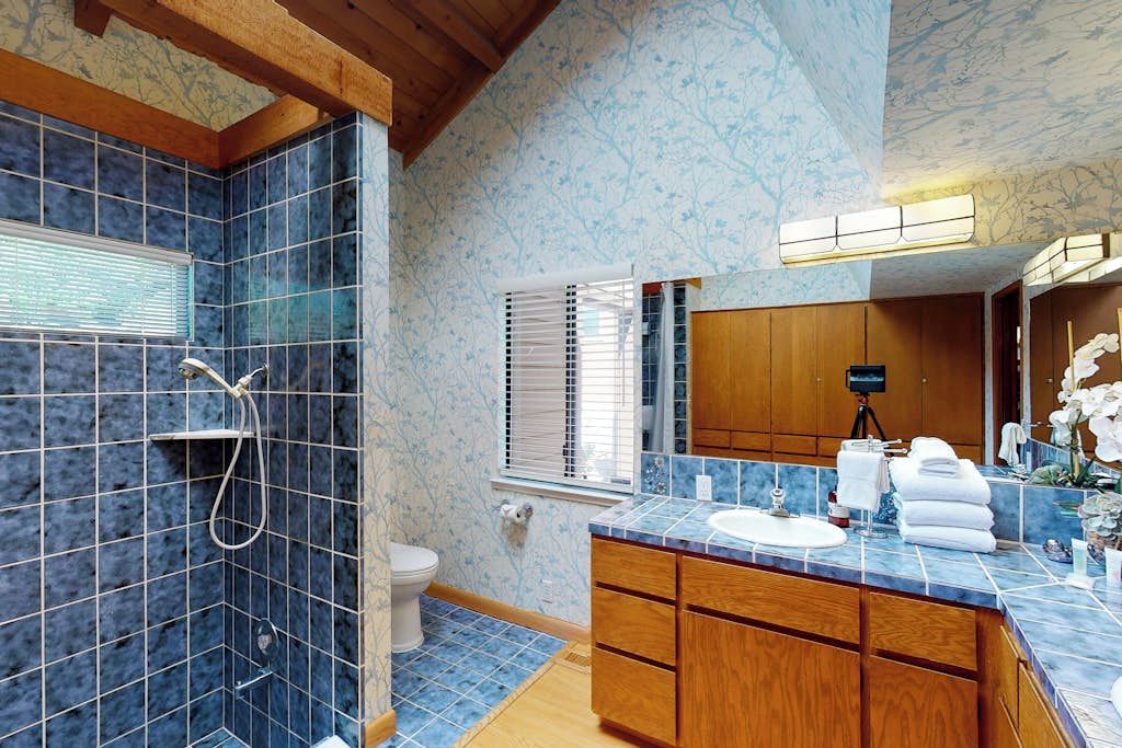 A bathroom with a shower, toilet, and vanity with a sink and mirror.