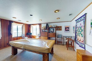 A room with a pool table, wooden cabinets, a television, and a wall with a patterned artwork. - Peters Lakefront - Dock, Pool Table & Lake Views (Bass Lake)