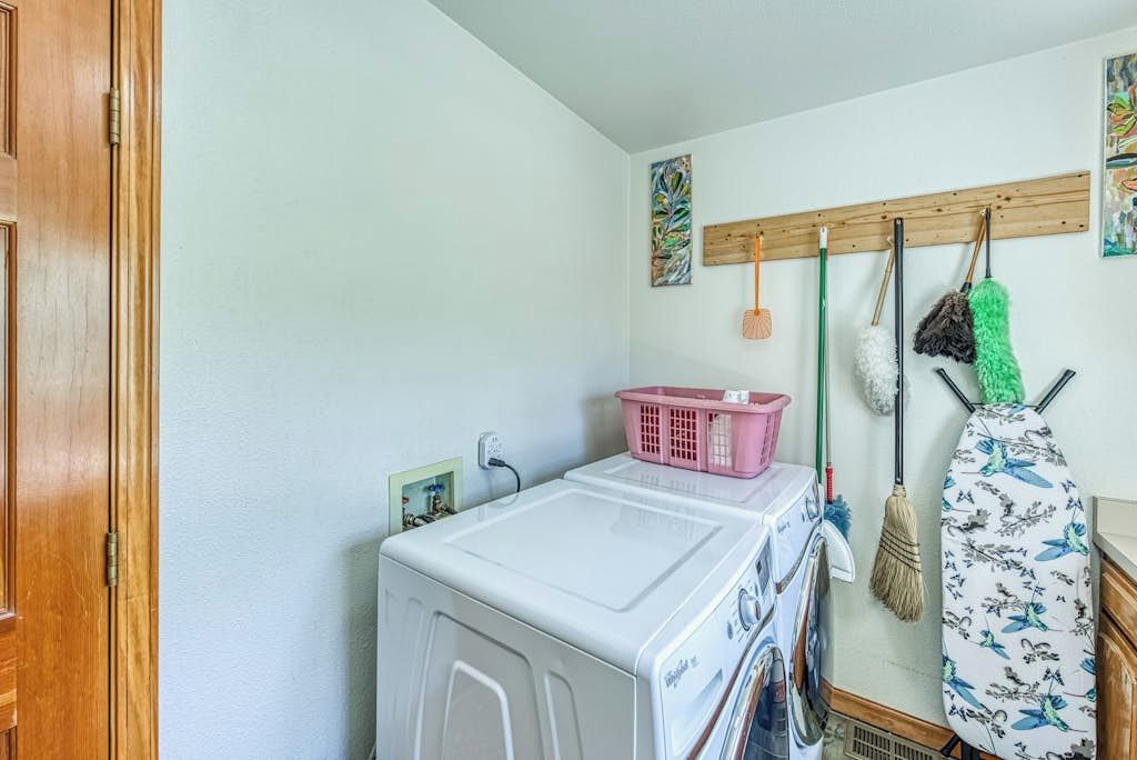 Un espace dédié à la lessive, comprenant un lave-linge, un étendoir et un support pour suspendre la serpillière.
