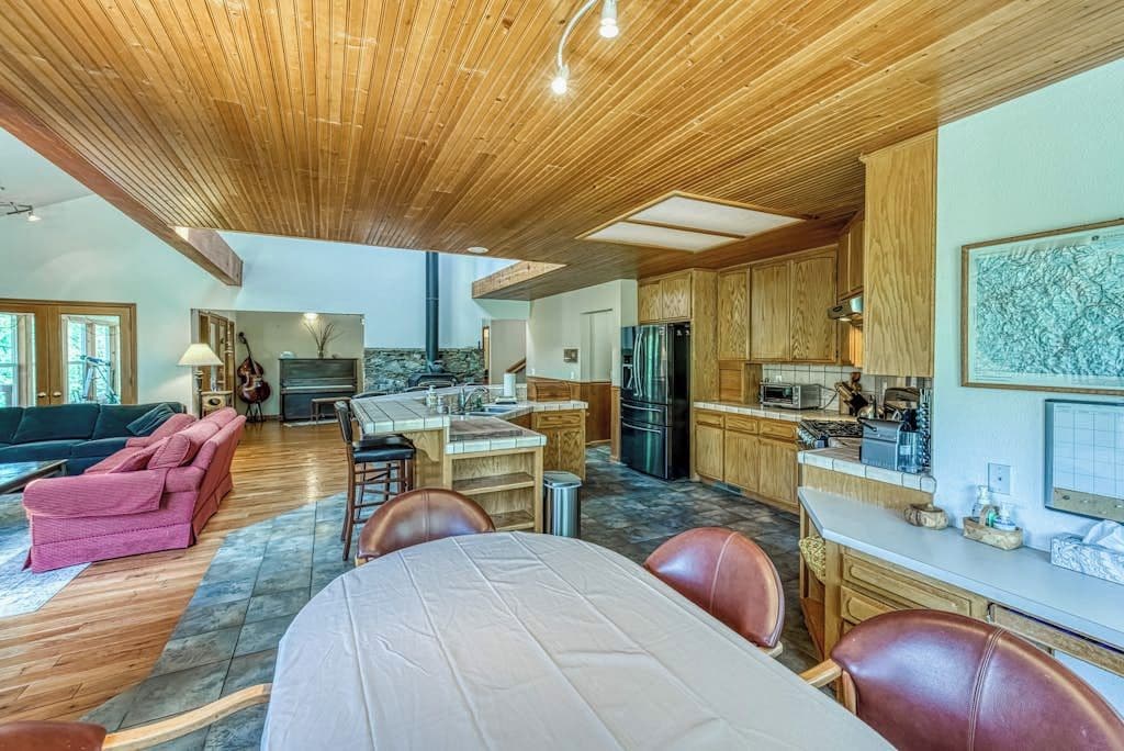 A spacious living area with a dining table, a kitchen with wooden cabinets, and a fireplace.