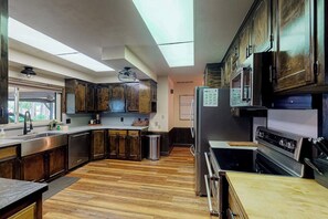 Eine moderne Küche mit dunklen Holzausziehtüren, Edelstahlgeräten und Holzboden.