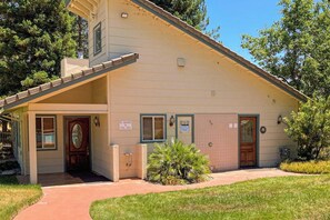 A single-story building with a front entrance, a covered porch, and a small front yard with a palm tree. - Willard Lake House - Heated Pool, Hot Tub & Views (Bass Lake)