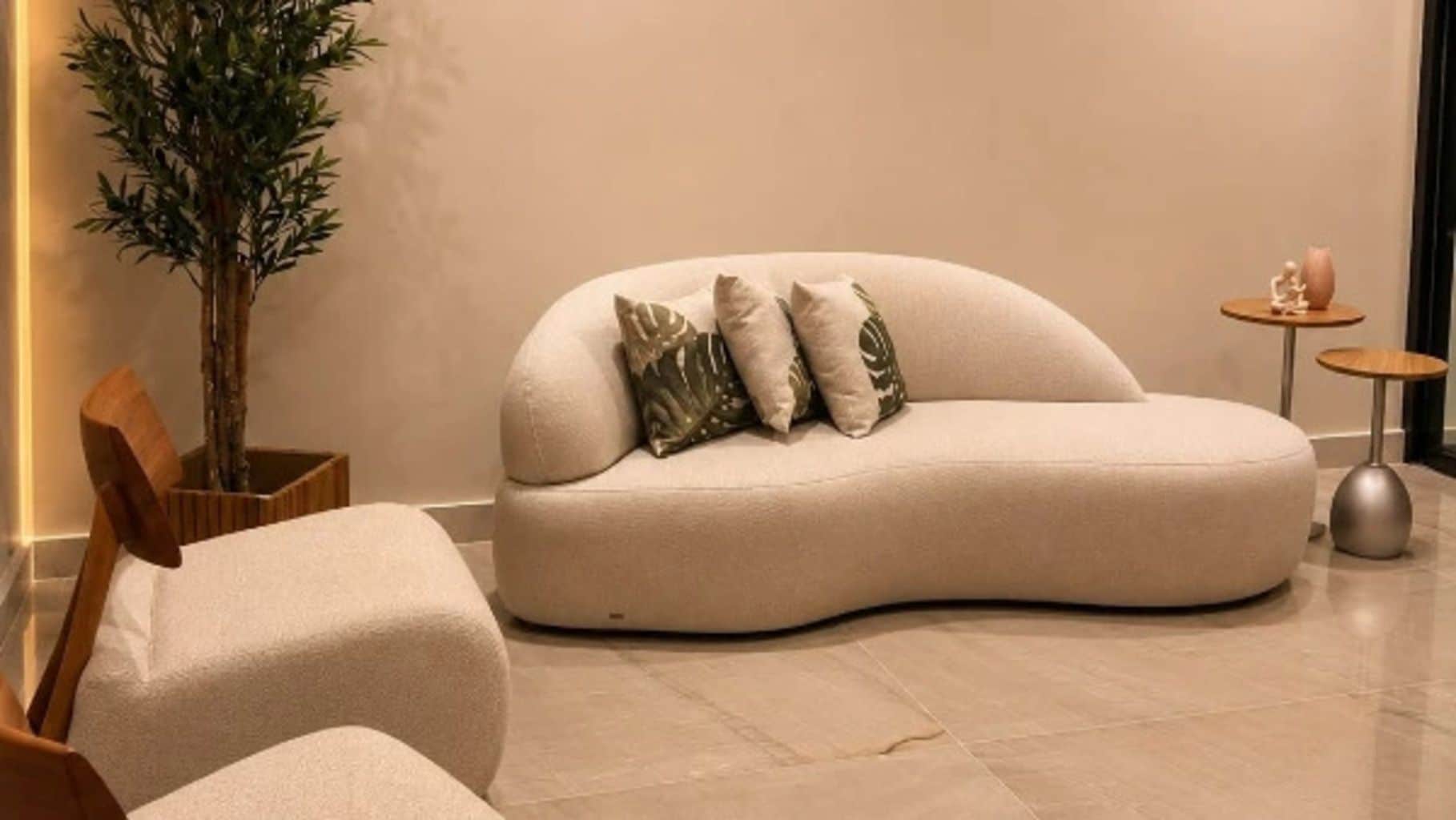 A modern living room with a curved sofa, a small side table, and a potted plant.