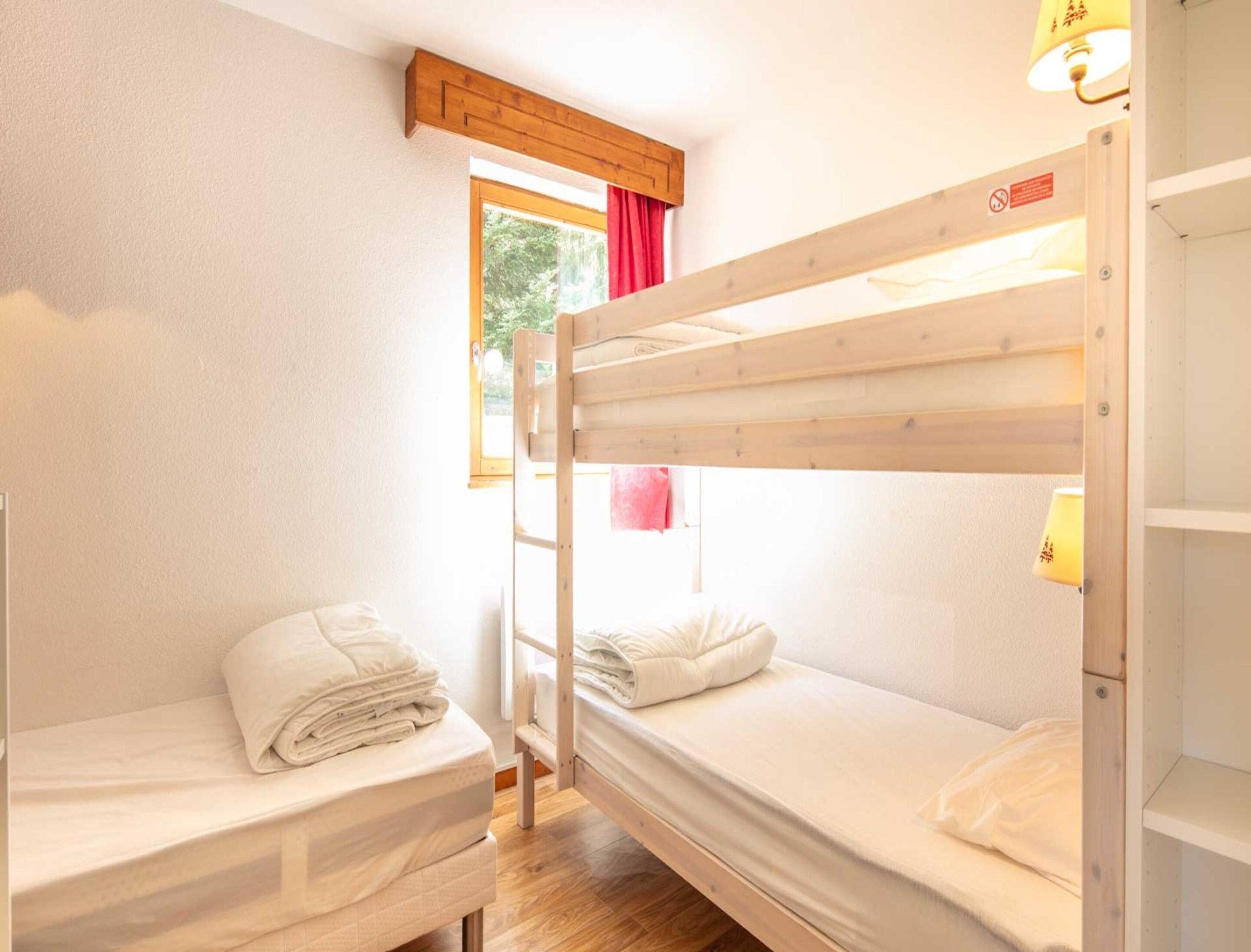 A bunk bed room with a window, a door, and a lamp.