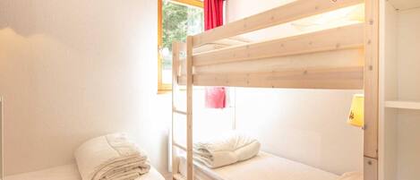 A bunk bed room with a window, a door, and a lamp.