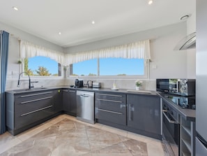 A modern kitchen with a dishwasher, coffee maker, and microwave. - Le Solévin · Vue vignes & Pic Saint-Loup - 4p (Jacou)