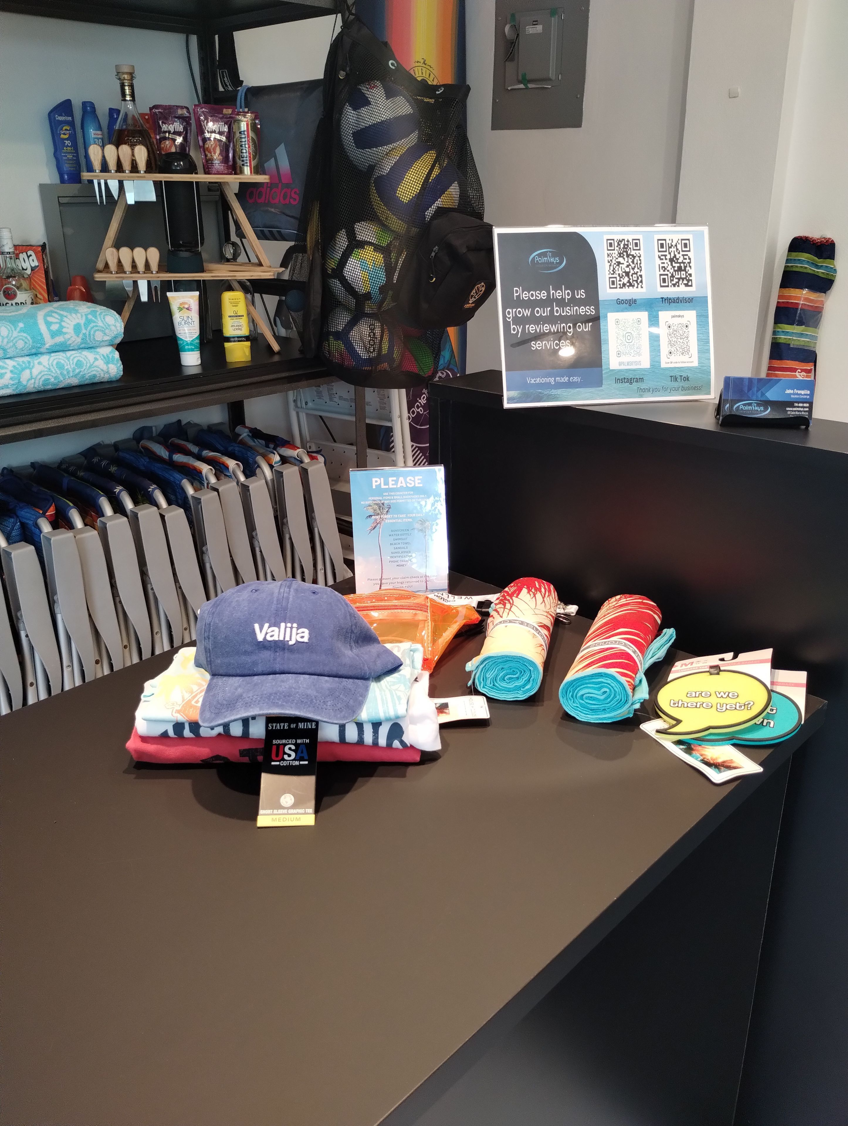 A display table with folded towels, a cap, and a sign asking for reviews.