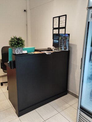 A reception desk with a computer monitor, a potted plant, and a framed certificate. - Suite 7 at Trinitaria House Hotel (San Juan)