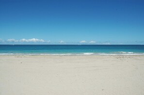 Een strand met helderblauw water en een zandstrand.