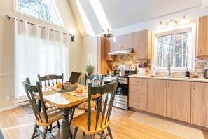 A modern kitchen with wooden cabinets, a central island, and a dining area with chairs. - Étoile Milante - Private Spa, Starry Sky & Mountains   (Milan)