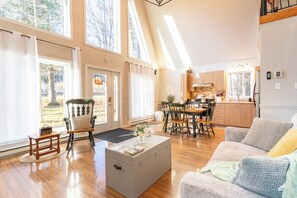 Ampla sala de estar com mesa de jantar, sofá e uma janela grande que proporciona iluminação natural.